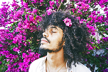 Portrait of Mixed Race man smelling flowers