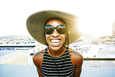 Black woman wearing sun hat and sunglasses on rooftop