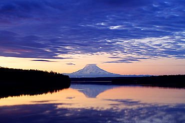 Reflection of clouds and mountain in river at sunset