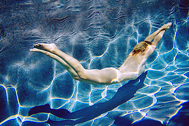 Naked Caucasian woman swimming underwater