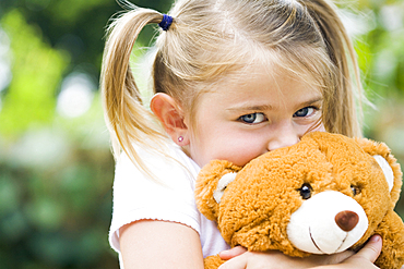 Caucasian girl hugging teddy bear