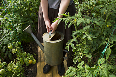 Caucasian woman holding watering can in greenhouse