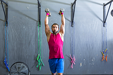 Mixed Race man lifting dumbbells in gymnasium