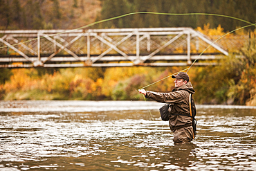 Caucasian man casting in river