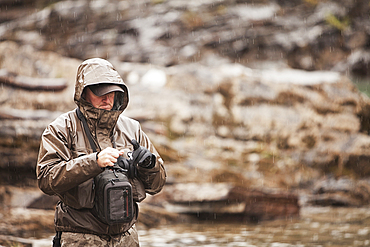 Caucasian man at river tying fishing fly