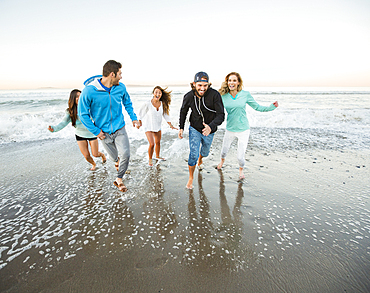 Smiling friends running on beach