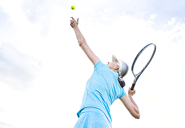 Caucasian woman serving tennis ball