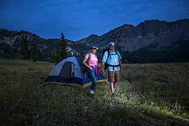 Caucasian couple wearing headlamps at mountain campsite