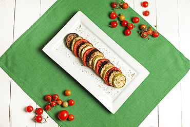 Plate of sliced food and tomatoes on plate and green linen