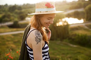 Smiling Caucasian woman wearing sun hat carrying sweater