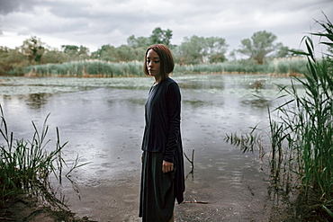 Caucasian woman standing near river in rain