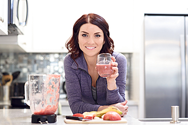 Caucasian woman drinking fruit smoothie in domestic kitchen