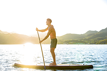 Caucasian man standing on paddleboard in river