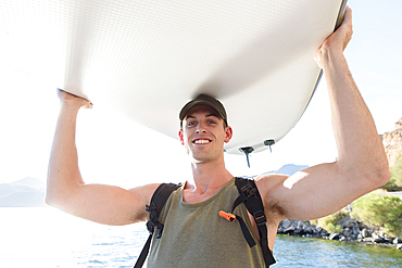 Caucasian man carrying paddleboard at river