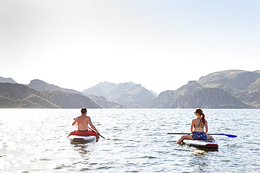 Couple sitting on paddleboards in river