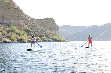 Caucasian couple on paddleboards in river