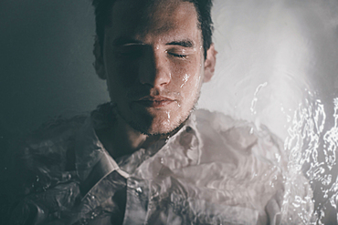 Caucasian man wearing shirt laying underwater in bathtub