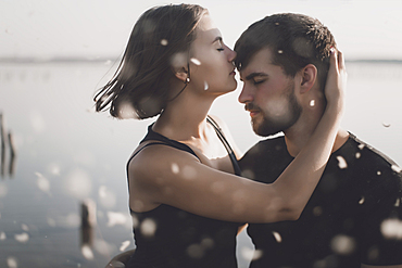 Water splashing on Caucasian couple hugging at lake