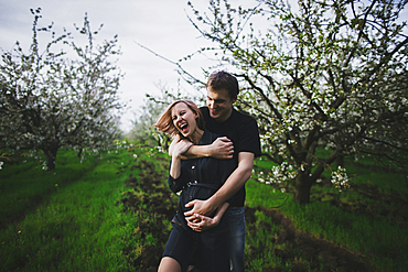 Caucasian couple hugging near trees