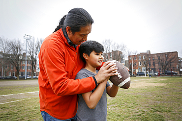 Native American father teaching son to throw football