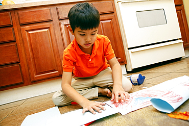 Native American sitting on kitchen floor making artwork