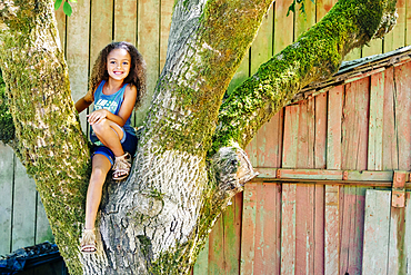 Mixed Race girl sitting in tree