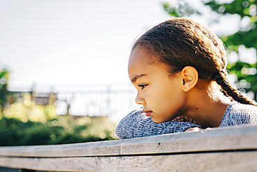 Pensive Mixed Race girl leaning on wooden railing