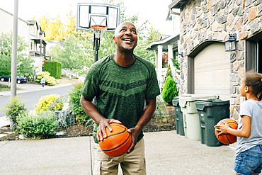 Father and daughter playing basketball in driveway