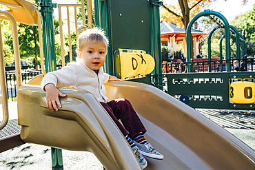 Portrait of Mixed Race boy sitting on playground slide