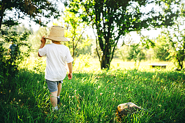 Caucasian boy wearing hat walking in grass