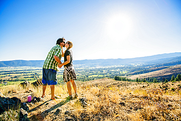 Caucasian couple standing on hill and kissing