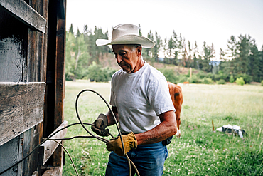 Caucasian farmer tying rope on fence