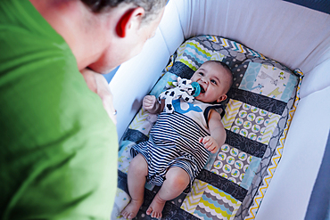 Father watching baby son in crib