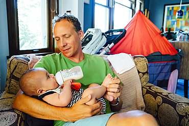 Father holding baby son drinking milk from bottle