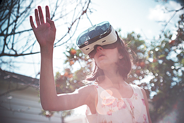 Mixed Race girl using virtual reality goggles outdoors