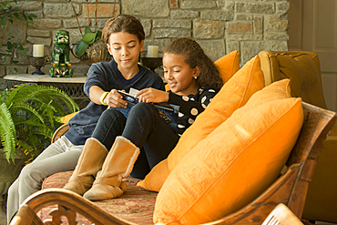 Mixed Race brother and sister reading book on sofa