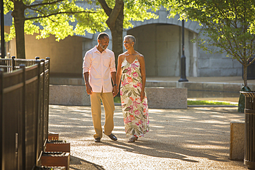 Black couple holding hands walking in park