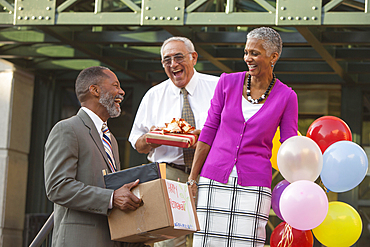 Co-workers celebrating with retiring man carrying belongings