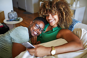 Smiling Black women cuddling on sofa