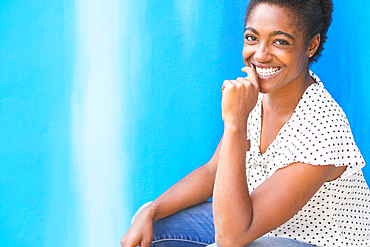 African American woman smiling near blue wall