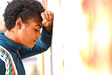 Pensive African American woman leaning on wall