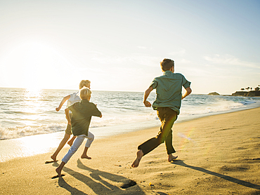 Caucasian brothers running on beach