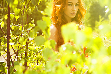 Caucasian woman posing behind foliage