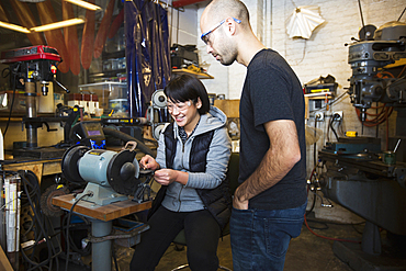 Mixed Race man using machinery in workshop