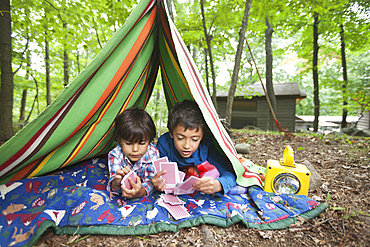 Mixed Race boys playing card game in blanket fort