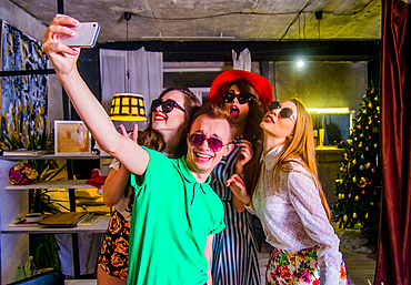 Fashionable Caucasian friends posing for cell phone selfie