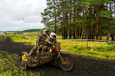 Caucasian racers on motorcycle with side car spraying dirt