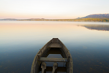 Empty rowboat on lake at sunset