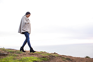 Indian woman wearing poncho walking on hill