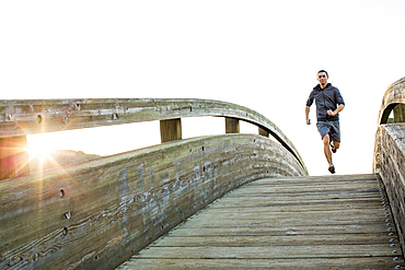 Mixed Race man running at top of curving footbridge